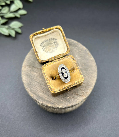 An oval cluster ring with diamonds and sapphires in platinum and yellow gold, in an antique ring box