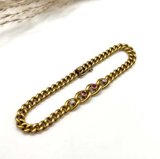 A yellow gold curb link bracelet with rubies and diamonds, on a white background