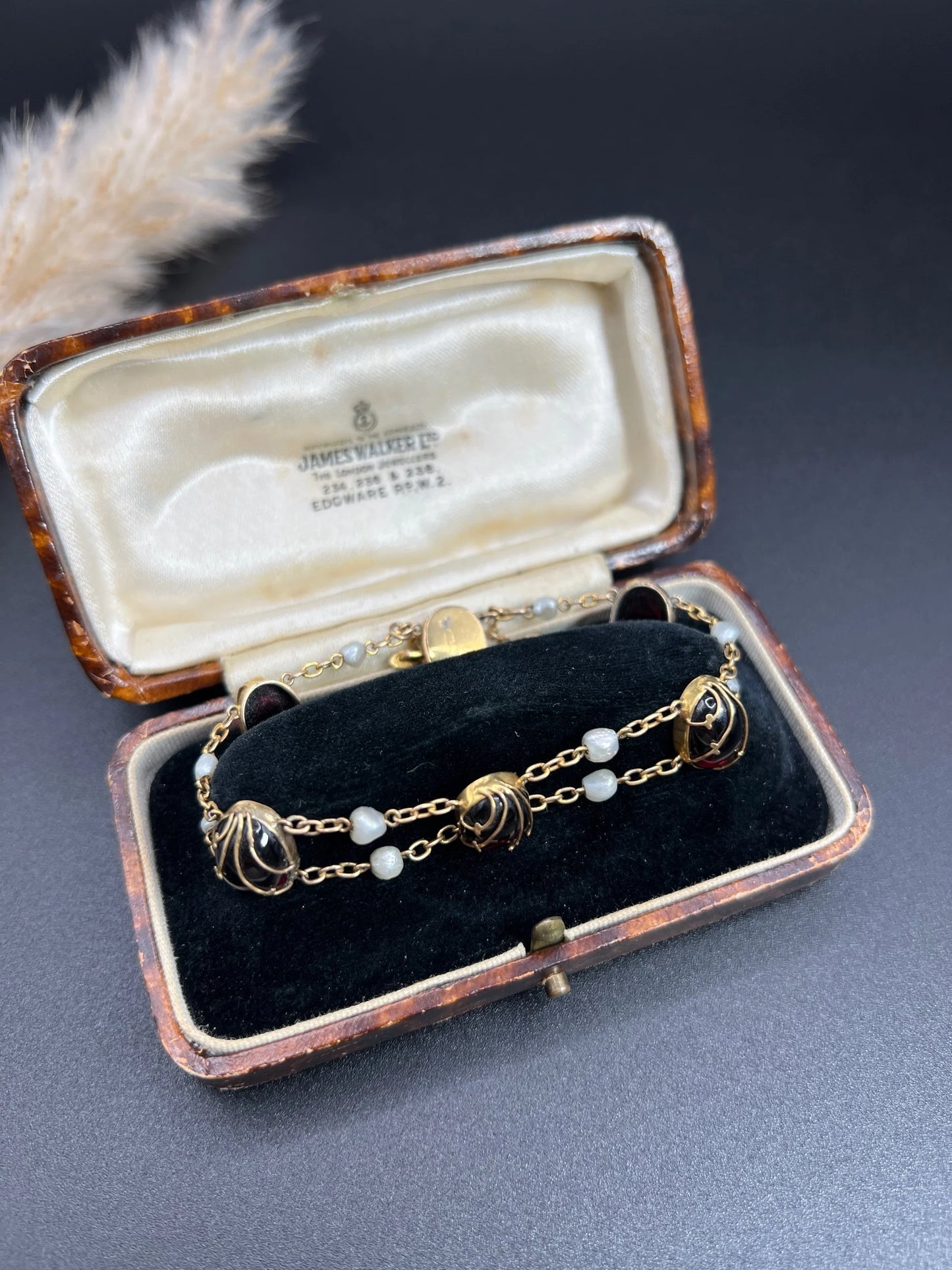 A yellow gold bracelet with oval cabochon garnets and white pearls, in a box