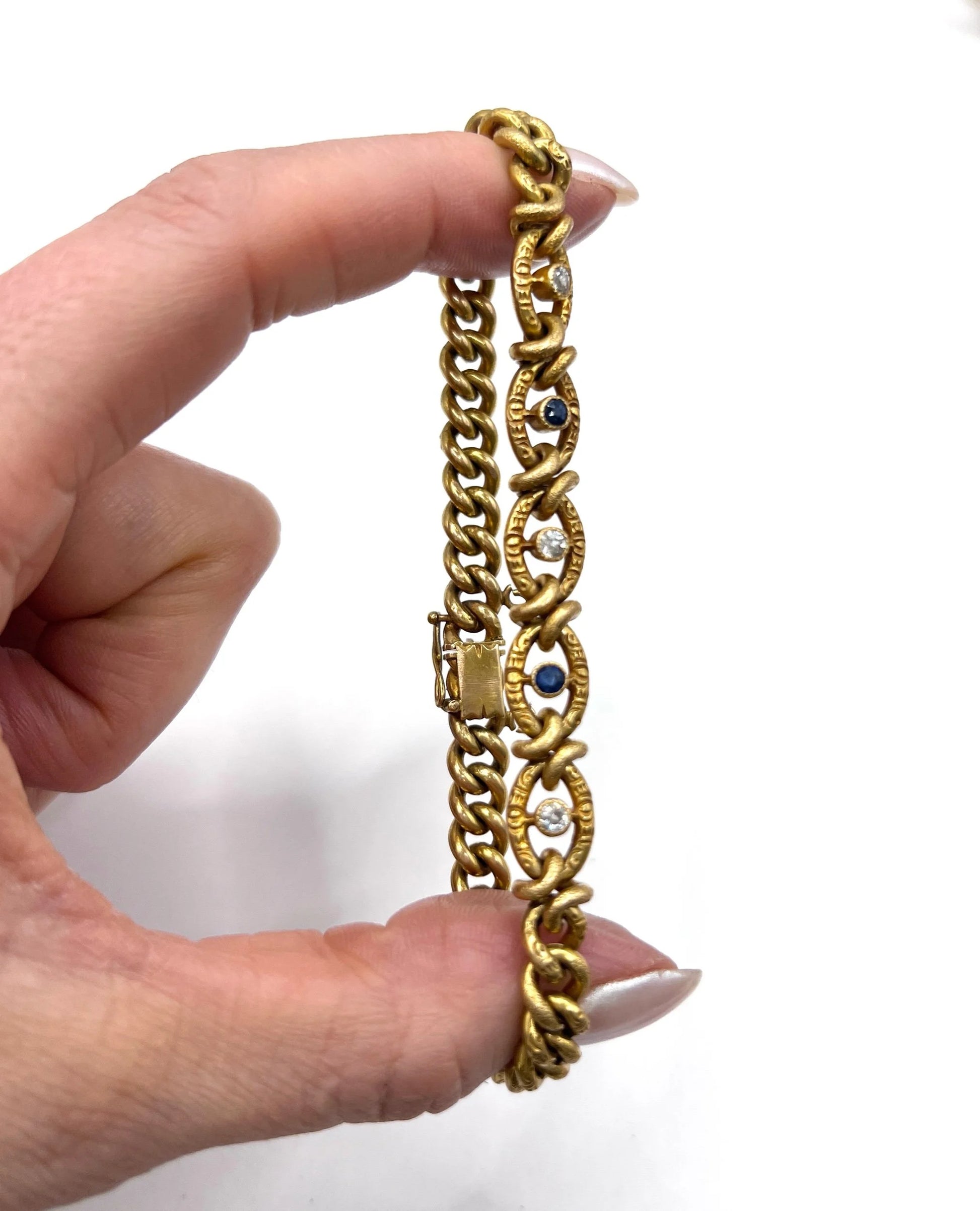 A sapphire and diamond fancy curb link bracelet in yellow gold, held in a hand