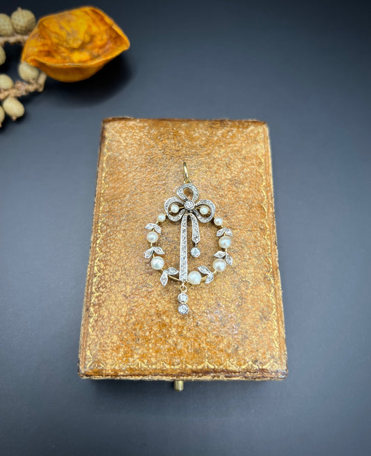 A pearl and diamond bow pendant in gold and platinum