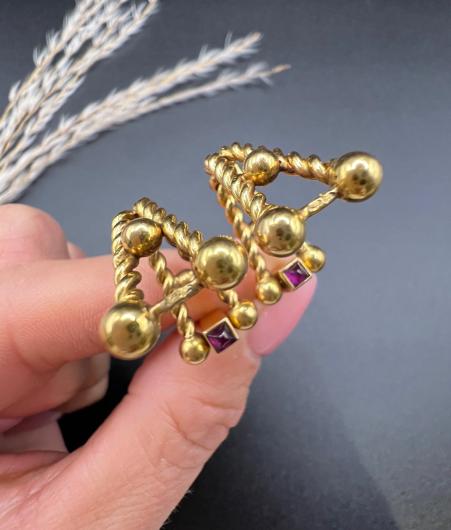 A pair of yellow gold ruby cufflinks, held in a hand