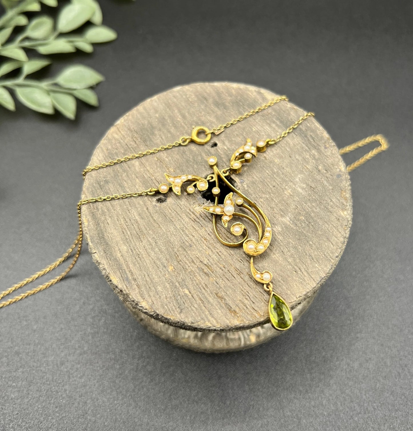 A yellow gold floral pendant necklace with pearls and a peridot drop