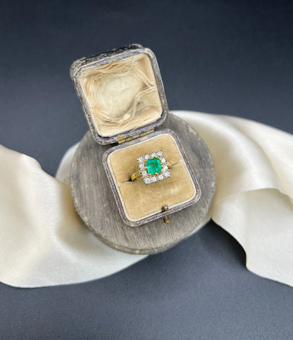 A square shaped emerald and diamond cluster ring in yellow and white gold, in a ring box