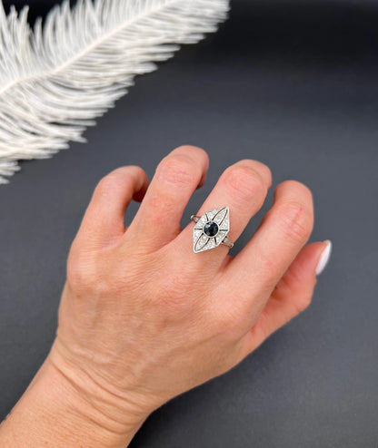 A navette shaped cluster cocktail ring with a sapphire centre surrounded by diamonds, in platinum, modelled on a hand