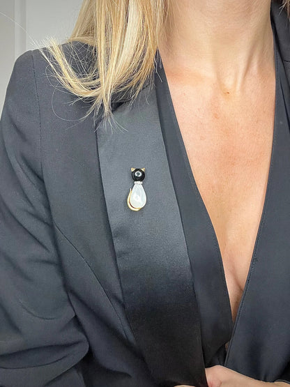 A cat-shaped brooch in yellow gold with black onyx, mother of pearl and a diamond set collar, modelled on a black jacket