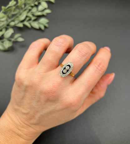 An oval cluster ring with diamonds and sapphires in platinum and yellow gold, modelled on a hand