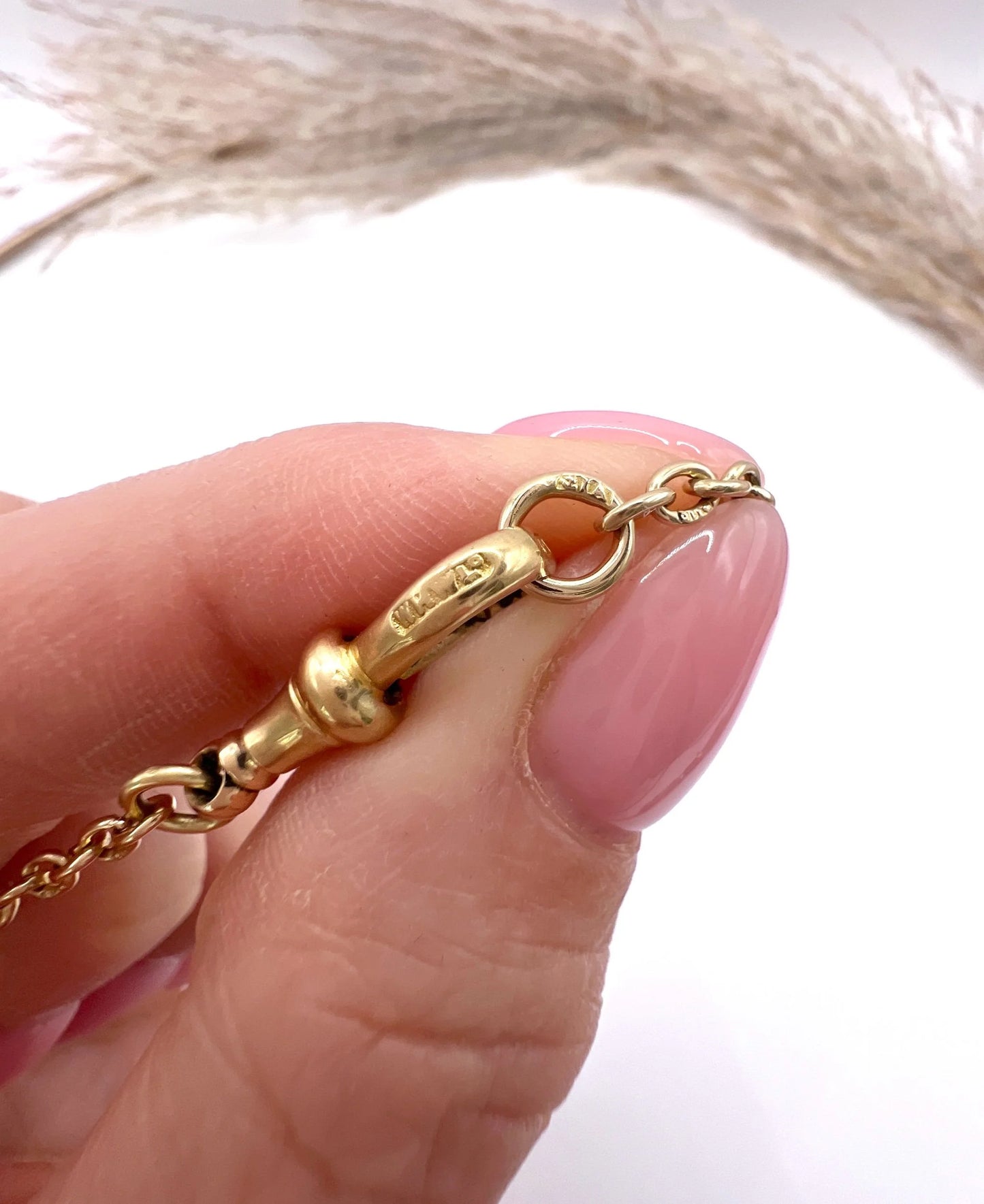 A yellow gold link bracelet with a lobster claw clasp, close-up, showing marks on the clasp and end rings