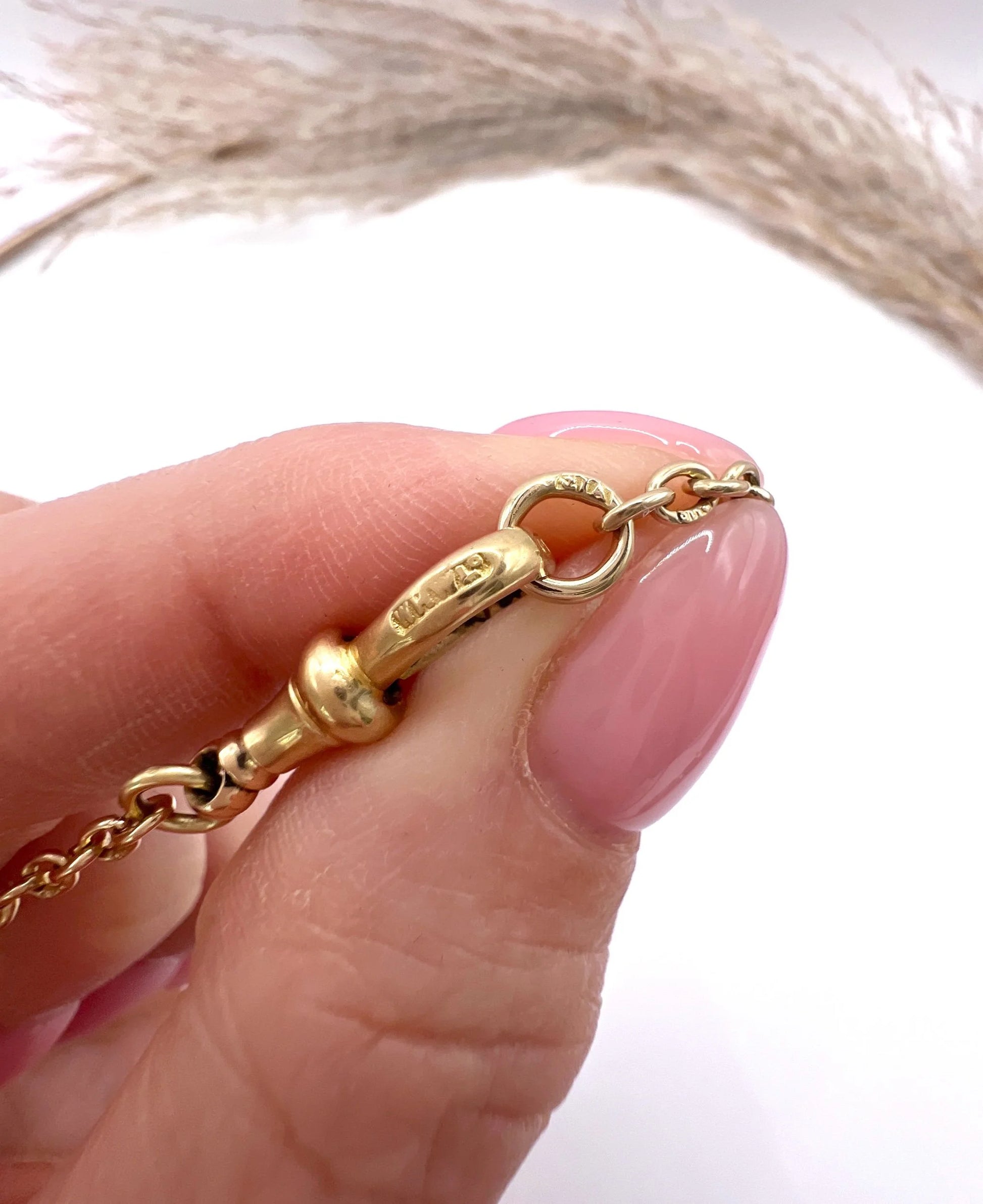 A yellow gold link bracelet with a lobster claw clasp, close-up, showing marks on the clasp and end rings