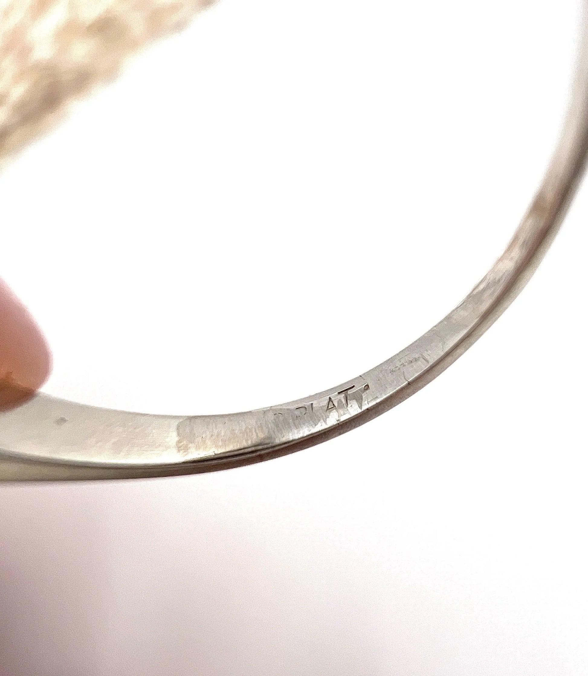 A faded PLAT stamp inside a ring shank