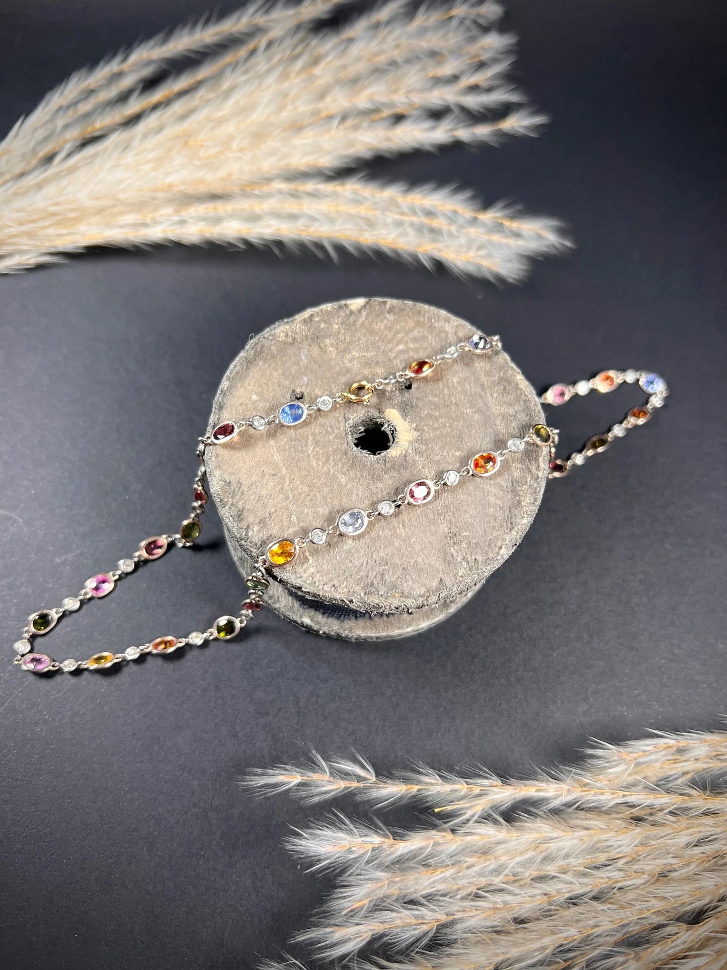 A coloured sapphire and diamond set necklace in platinum and gold, on a wooden object