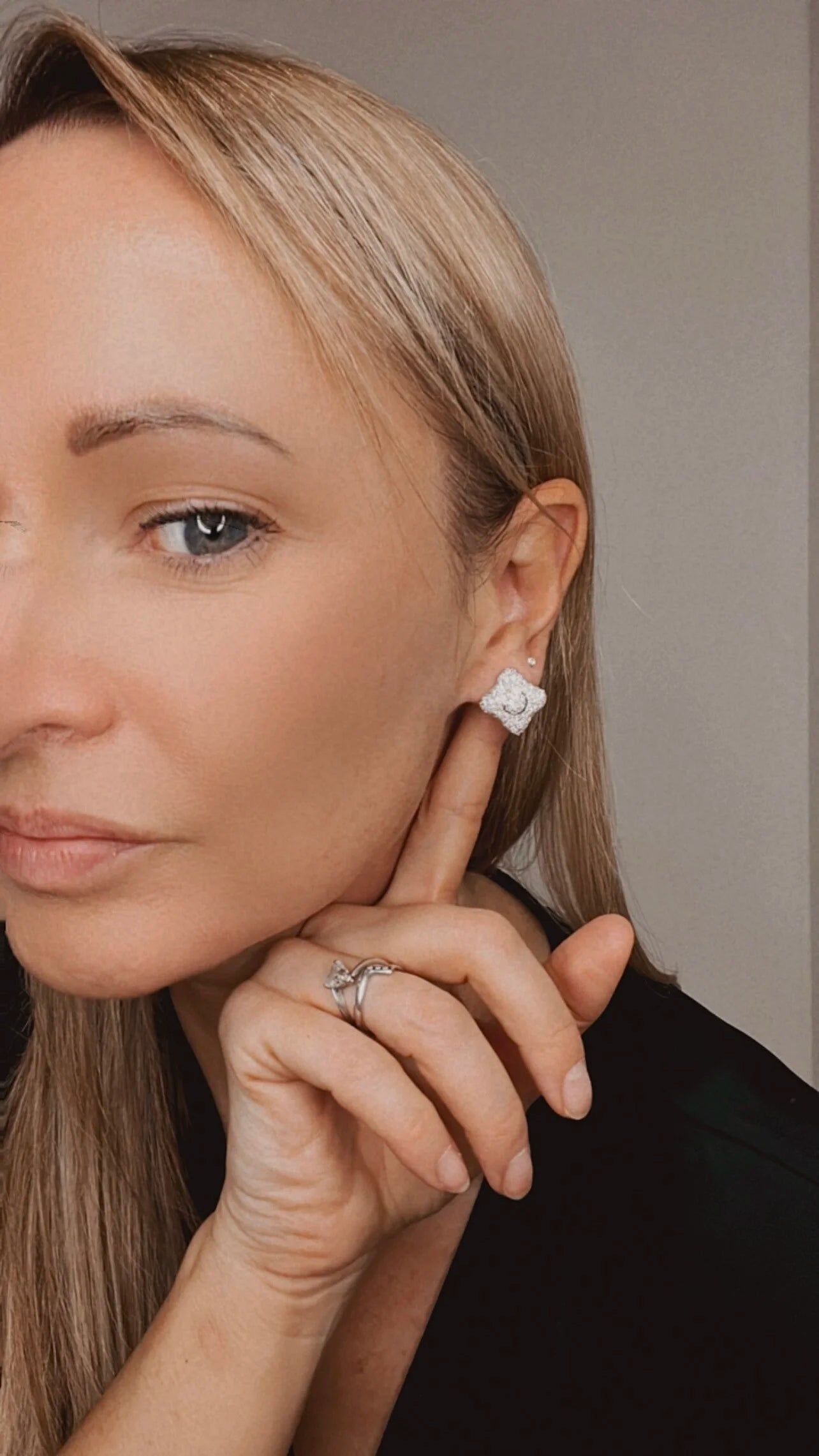 A diamond cluster stud earring, modelled by a woman wearing a black top