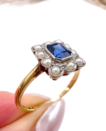 A sapphire and pearl cluster ring in yellow gold and platinum, held in a hand