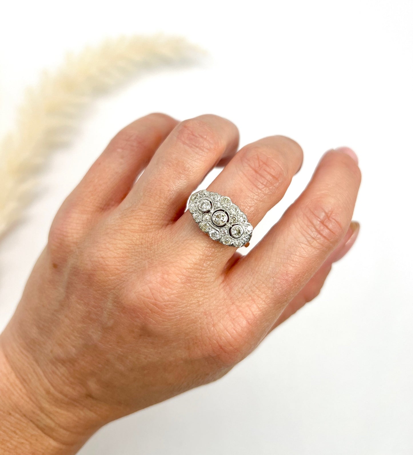 A diamond triple cluster ring in yellow and white gold, modelled on a hand