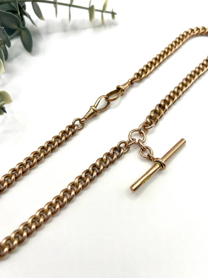 A rose gold curb link Albert chain on a white background