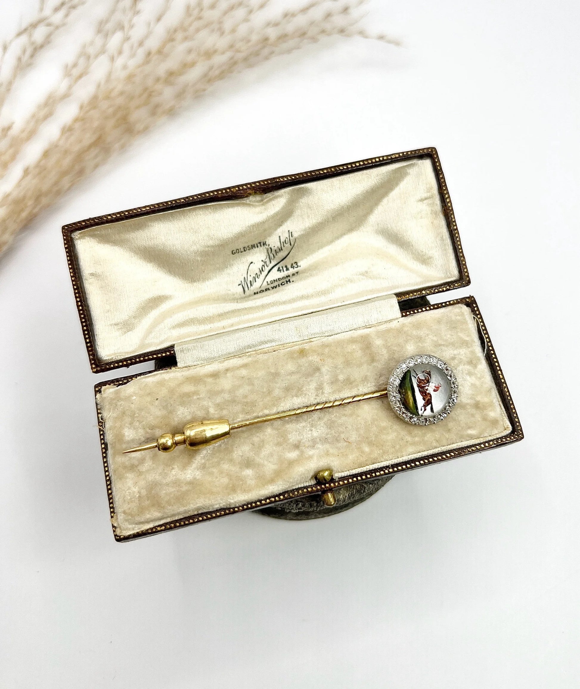 An antique Essex glass and diamond stick pin depicting a jockey riding a horse, in a box