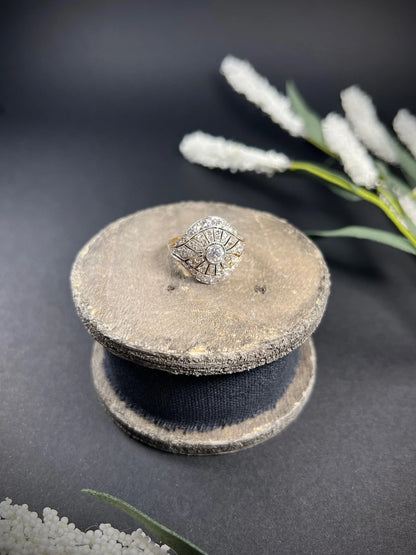 A diamond cocktail ring in yellow and white metal sat on top of a wooden object