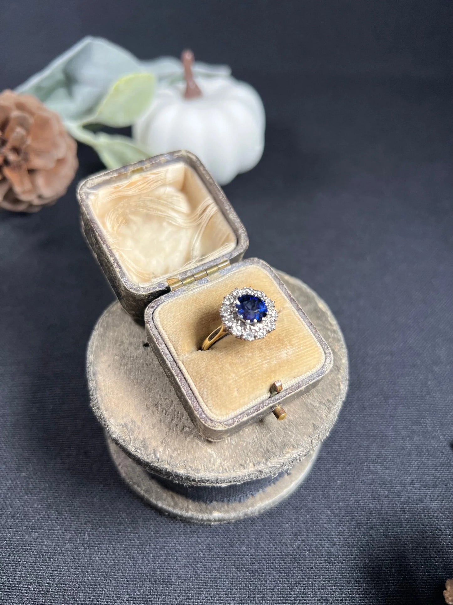 A round sapphire and diamond cluster ring, in an antique ring box