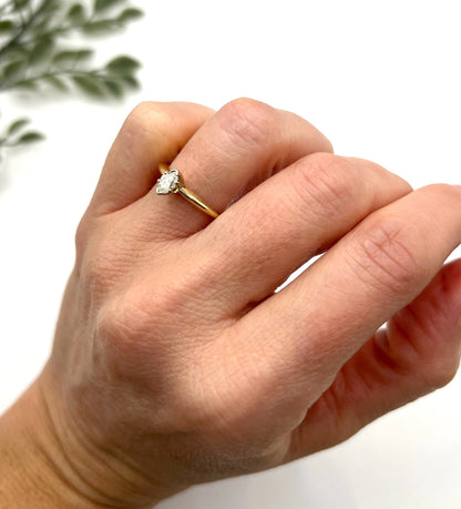 A marquise diamond solitaire ring in yellow and white gold, modelled on a hand
