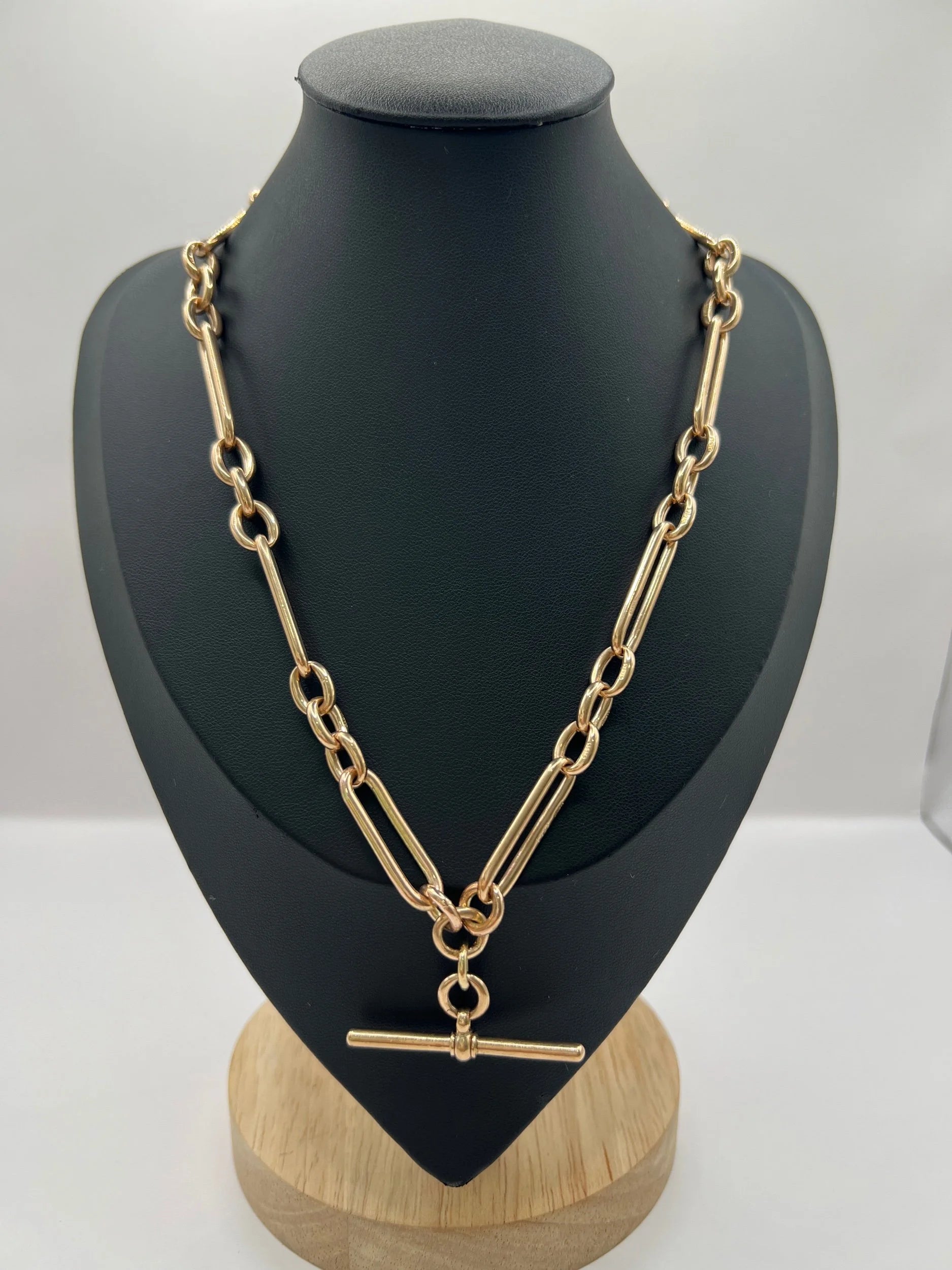 A rose gold trombone and fetter link Albert chain, on a black jewellery bust