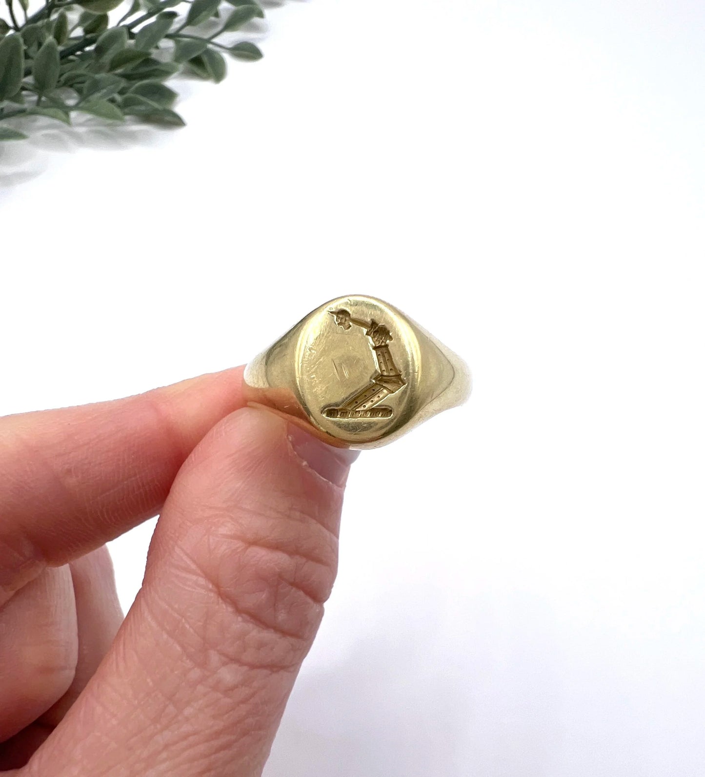 A yellow gold oval signet ring with a seal engraved heraldic crest