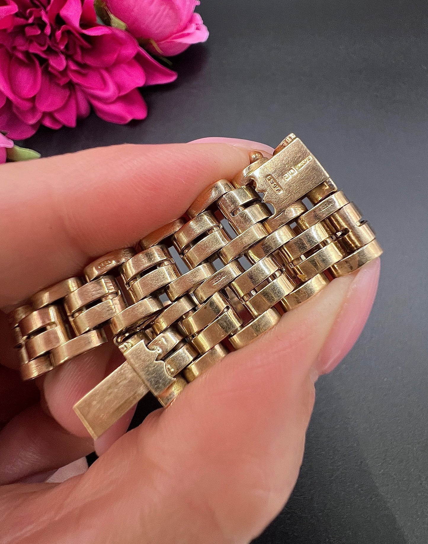A yellow gold link bracelet, held in a hand