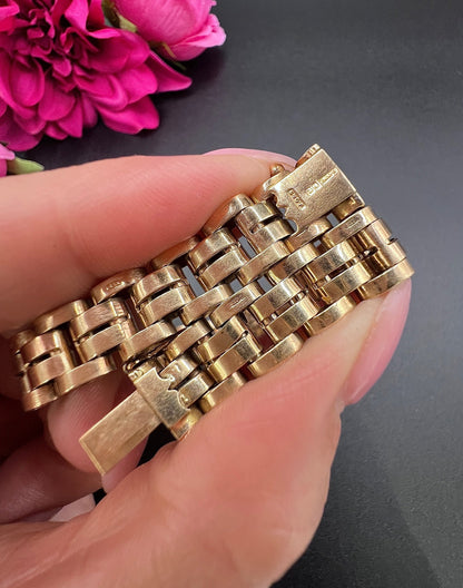 A yellow gold link bracelet, held in a hand
