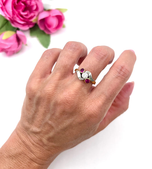 A three stone ruby and diamond crossover ring in platinum and yellow gold, modelled on a hand