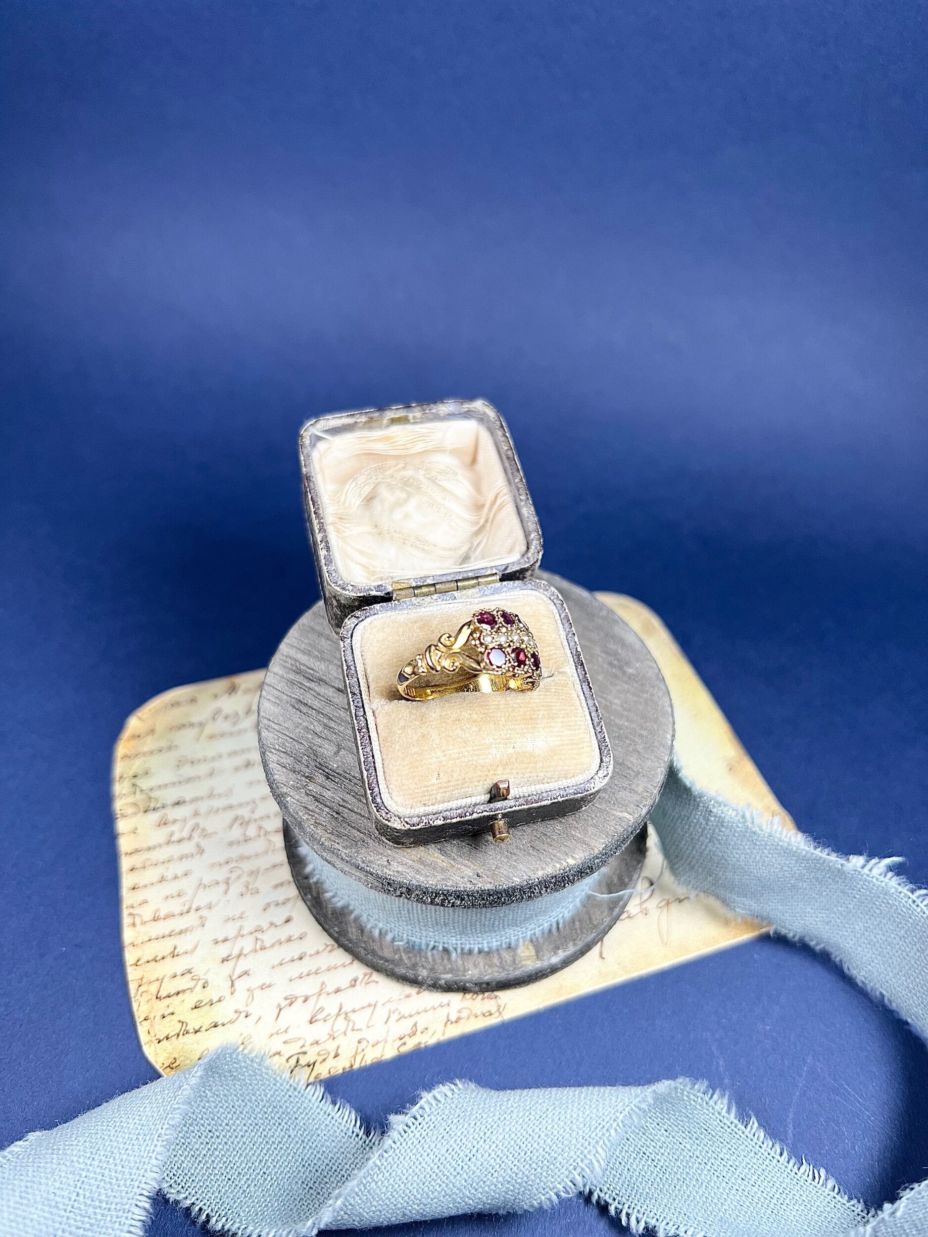 A yellow gold triple row ring with garnets and seed pearls, in a box