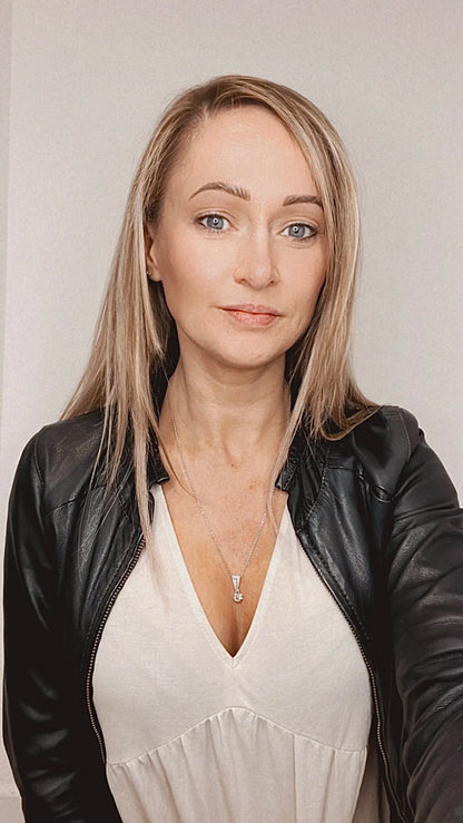 An old cut diamond pendant in white metal with a matching chain, modelled by a woman wearing a white top and black jacket