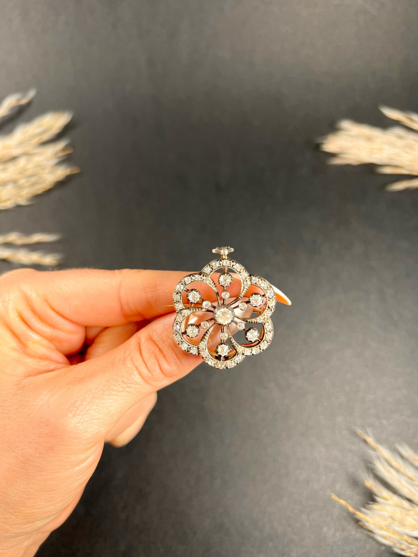 A floral design diamond set pendant/brooch, held in a hand