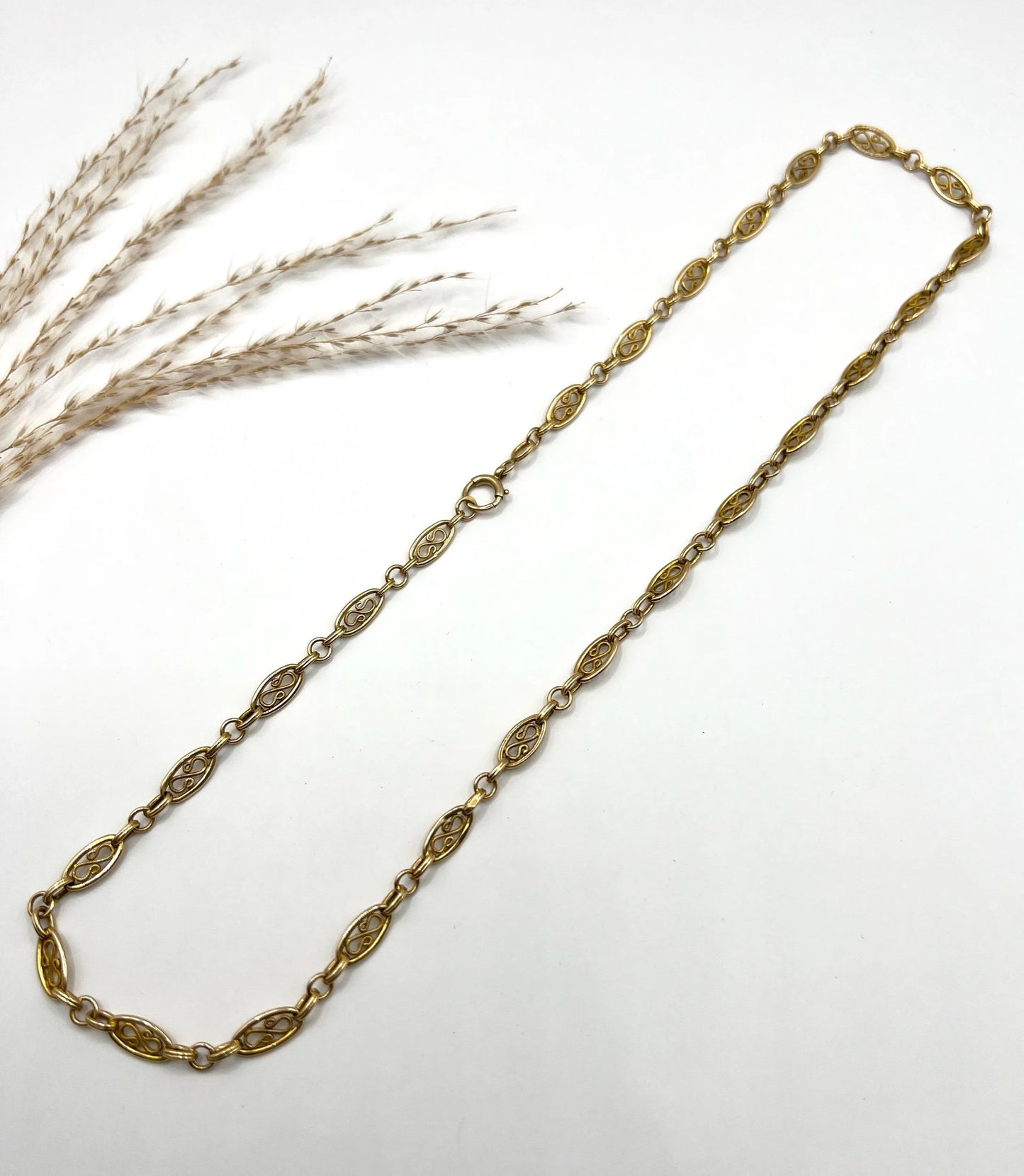 A yellow gold fancy link chain on a white background