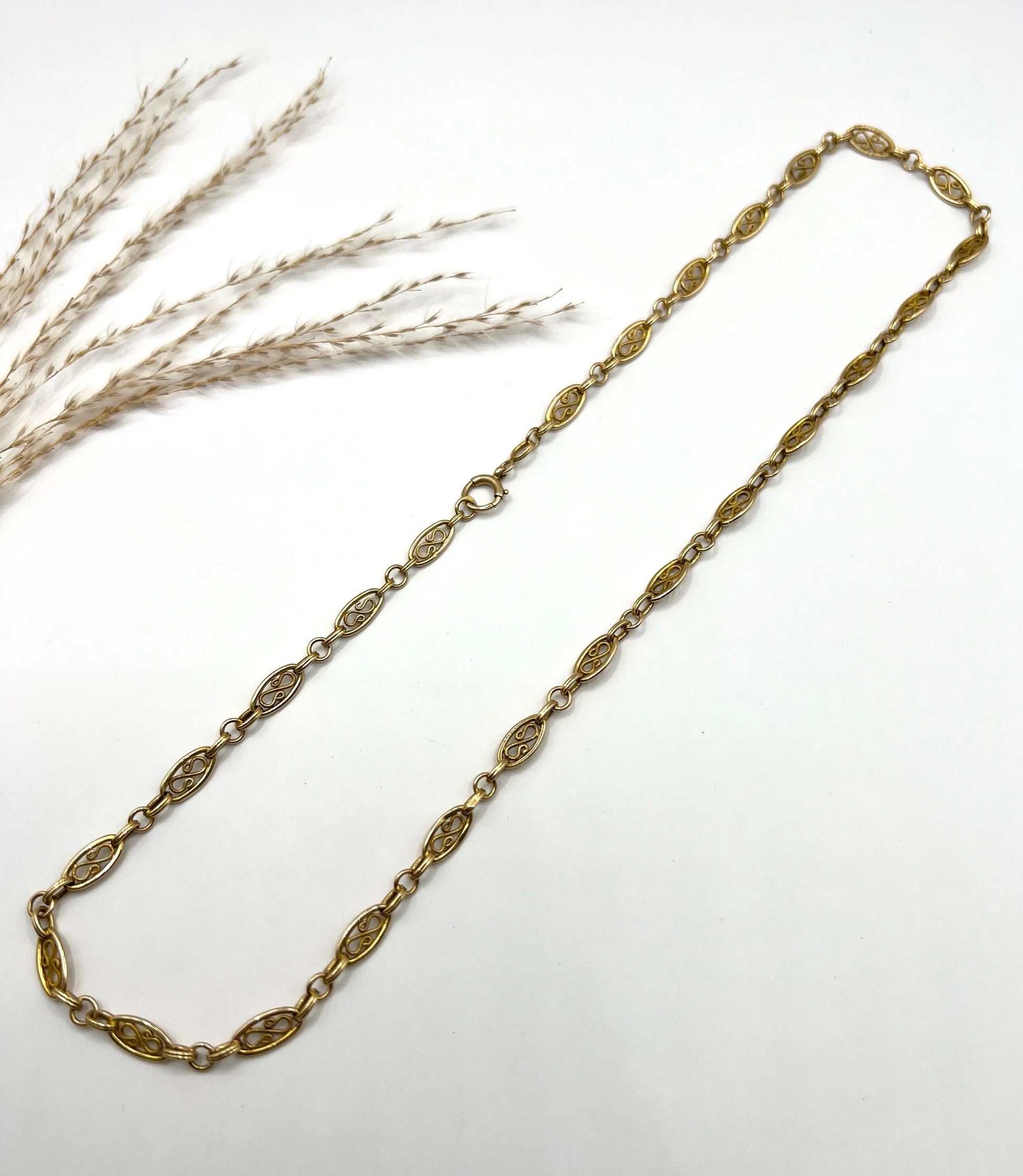 A yellow gold fancy link chain on a white background