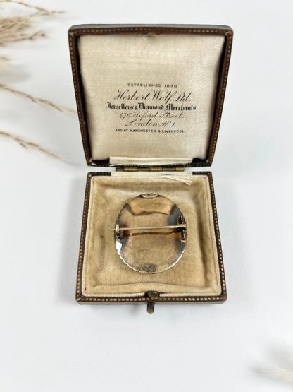 An oval gold brooch, in an antique box