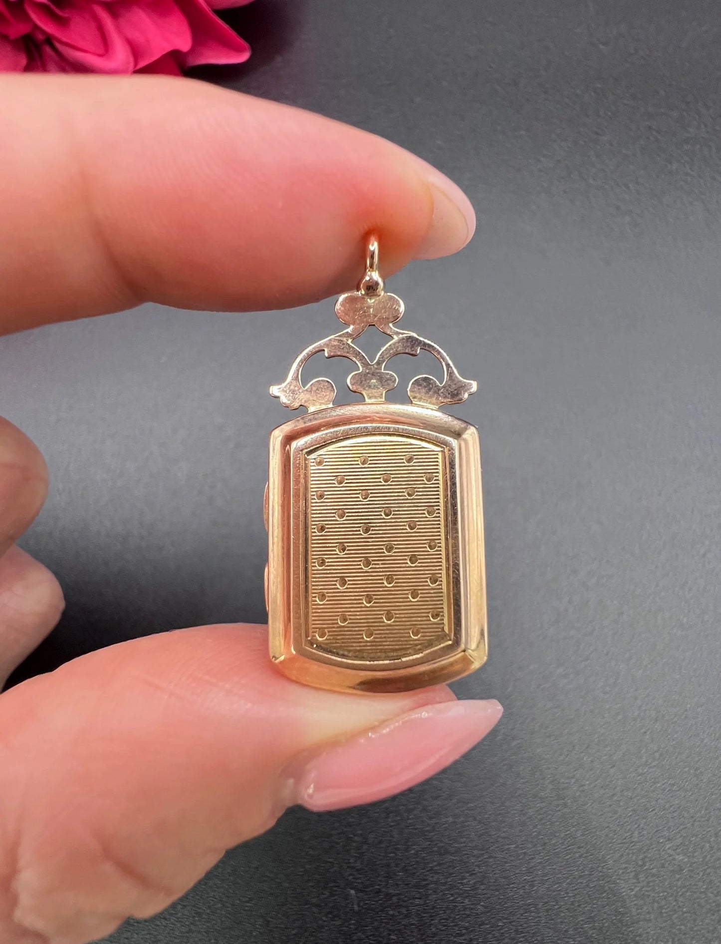 A yellow gold ornate locket with engraving to the back