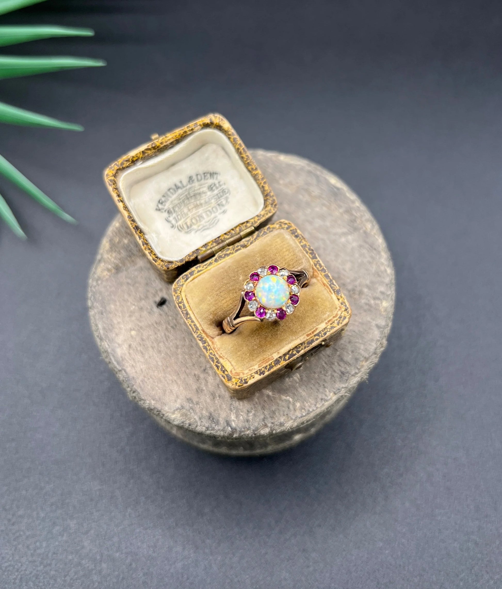 A daisy style cluster ring in rose gold with opal, ruby and diamond, in an antique ring box