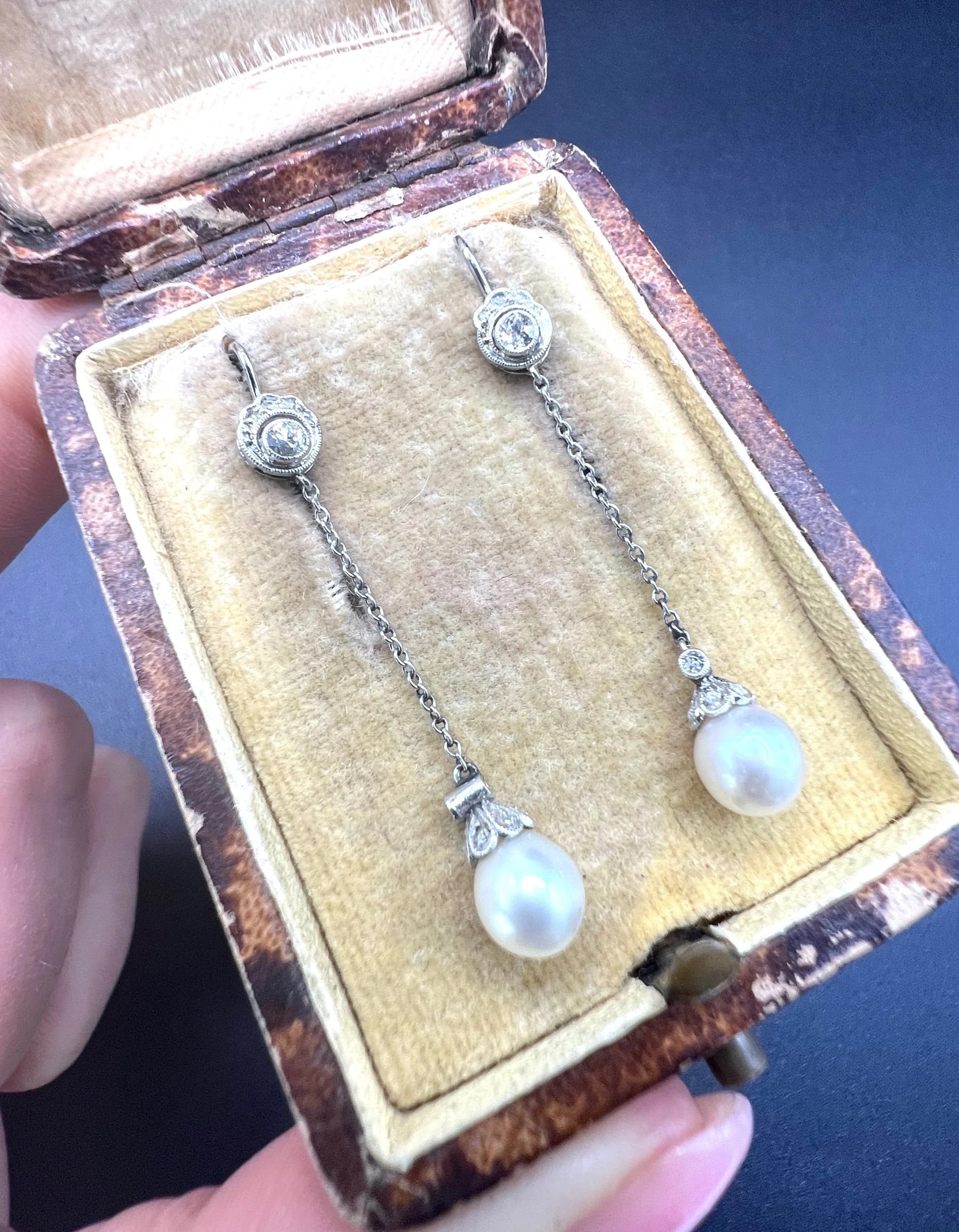 A pair of long drop platinum earrings with pearls and diamonds, in an antique box
