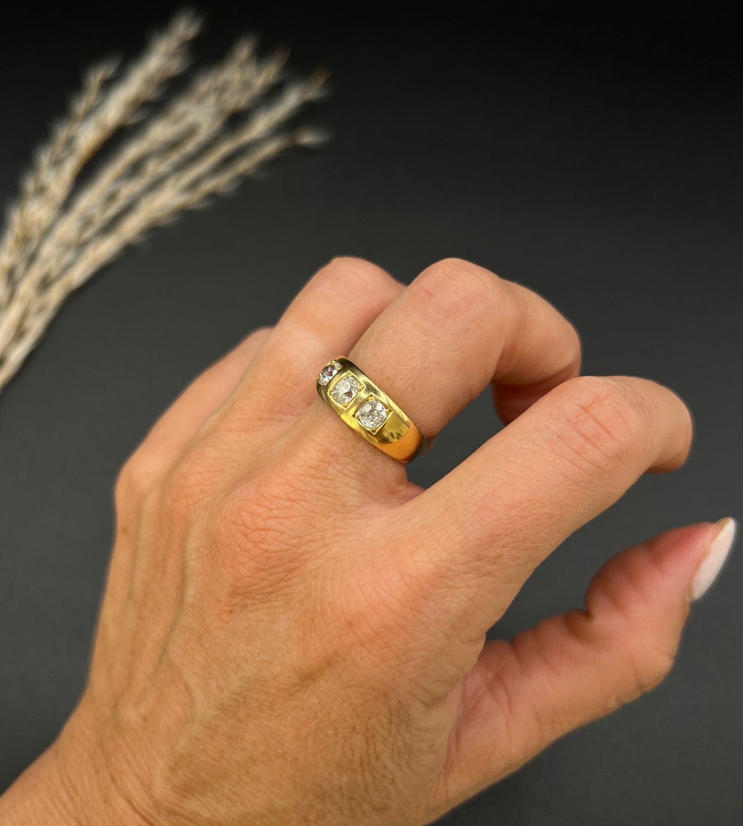 A three stone old cut diamond ring in yellow gold, modelled on a hand