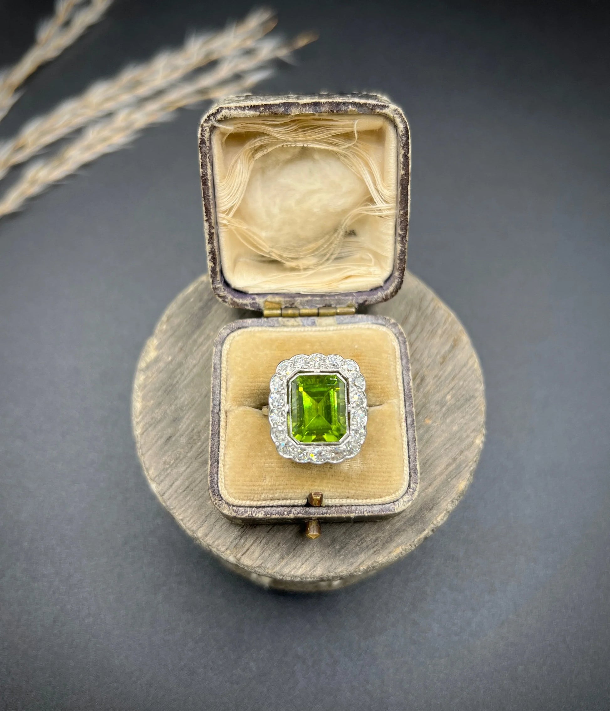 A cushion shaped peridot and diamond cluster ring in white metal, in an antique ring box