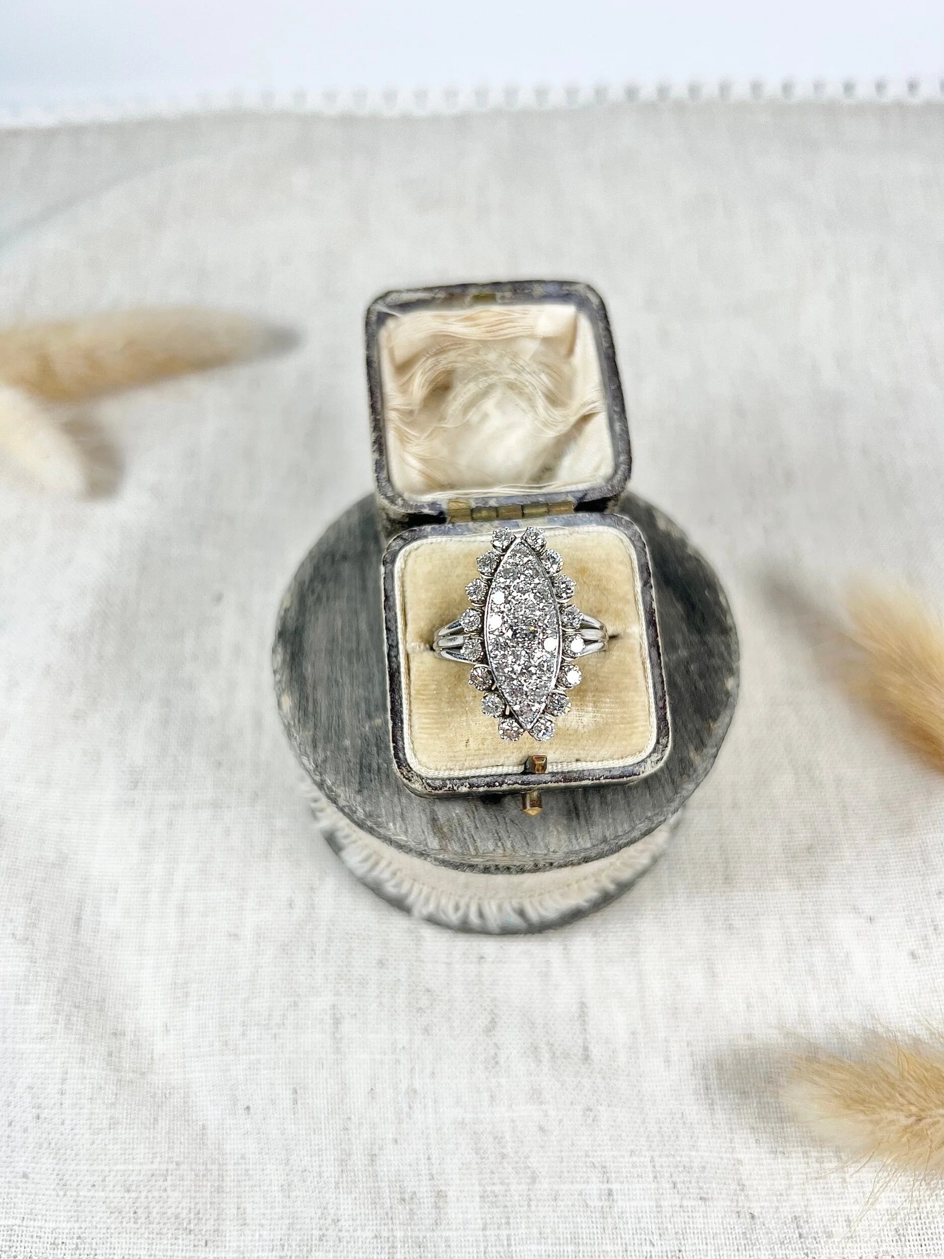 A navette shaped diamond cluster ring in white metal, in an antique ring box