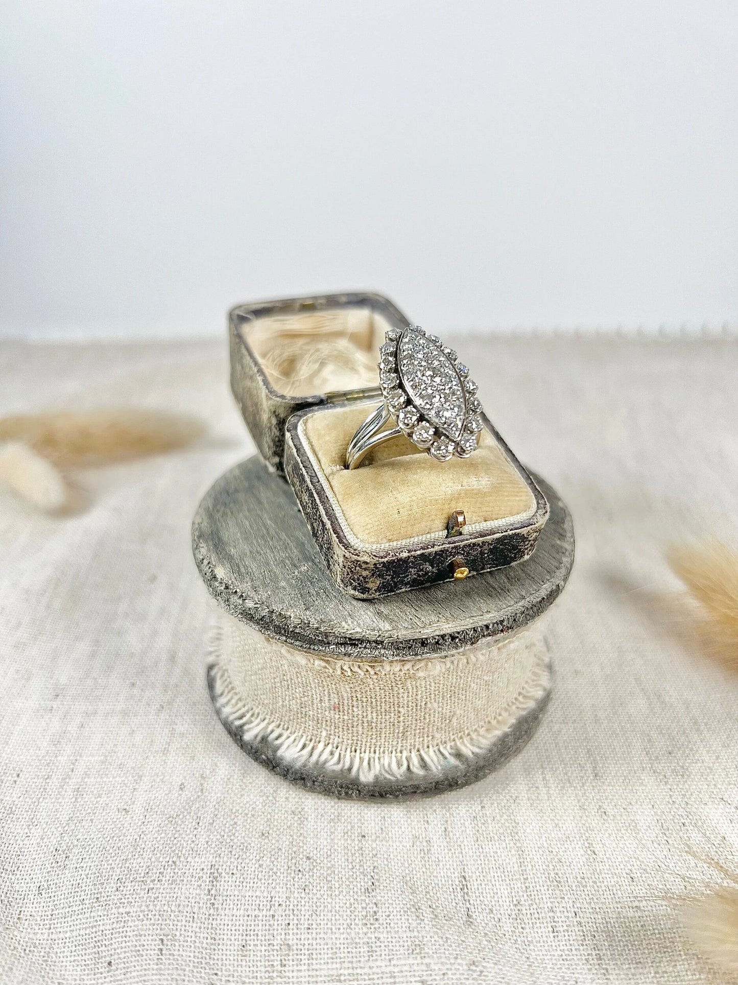 A navette shaped diamond cluster ring in white metal, in an antique ring box