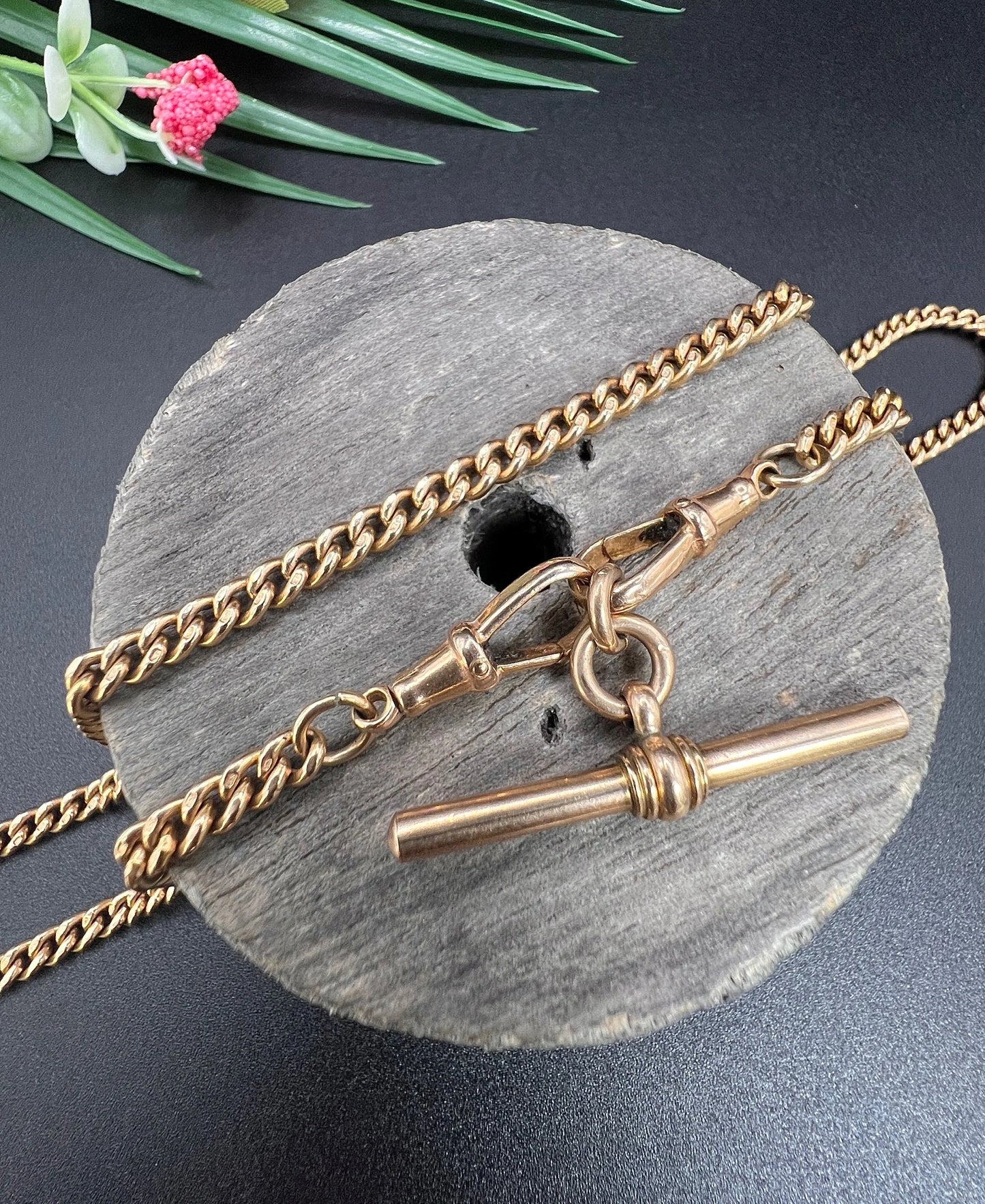 A gold curb link Albert chain, on a wooden spool