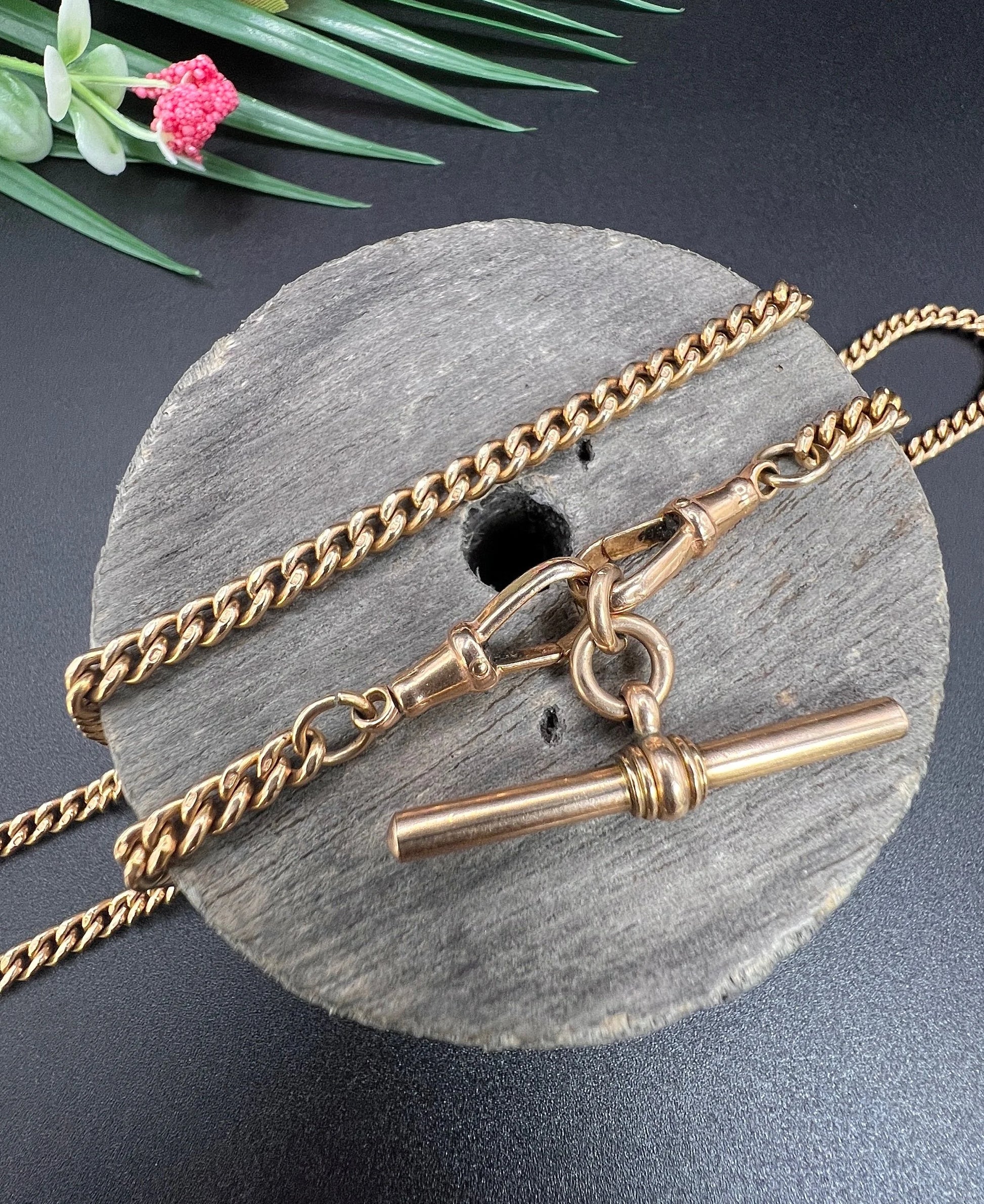 A gold curb link Albert chain, on a wooden spool