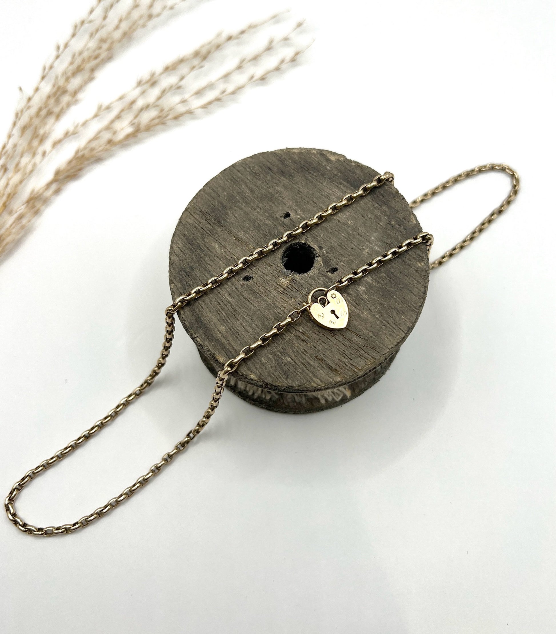 A gold belcher link chain with a heart shaped padlock clasp pendant
