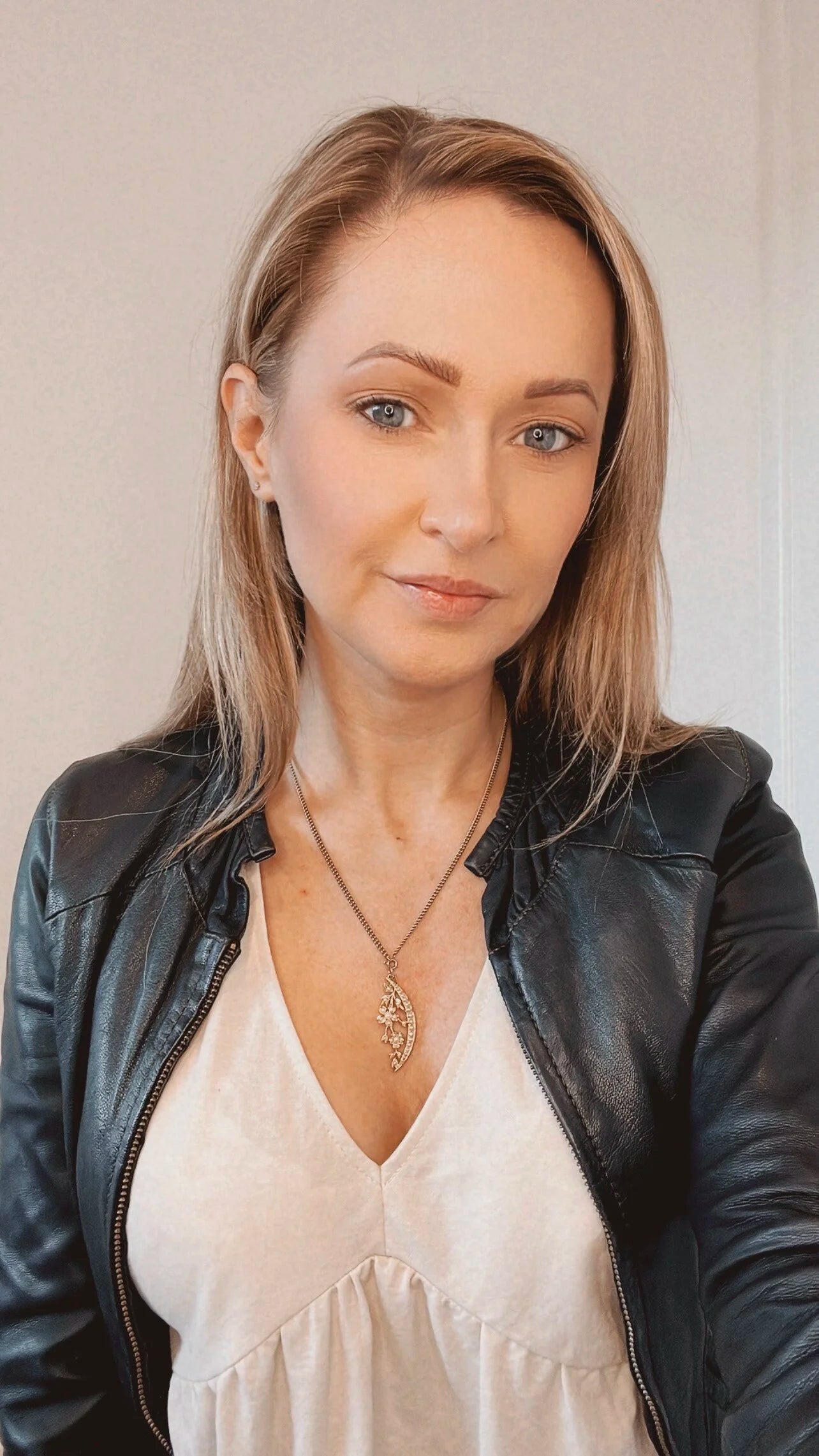 A yellow gold floral crescent pendant with pearls, with a chain, modelled by a woman