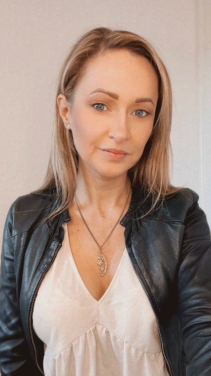 A yellow gold floral crescent pendant with pearls, with a chain, modelled by a woman