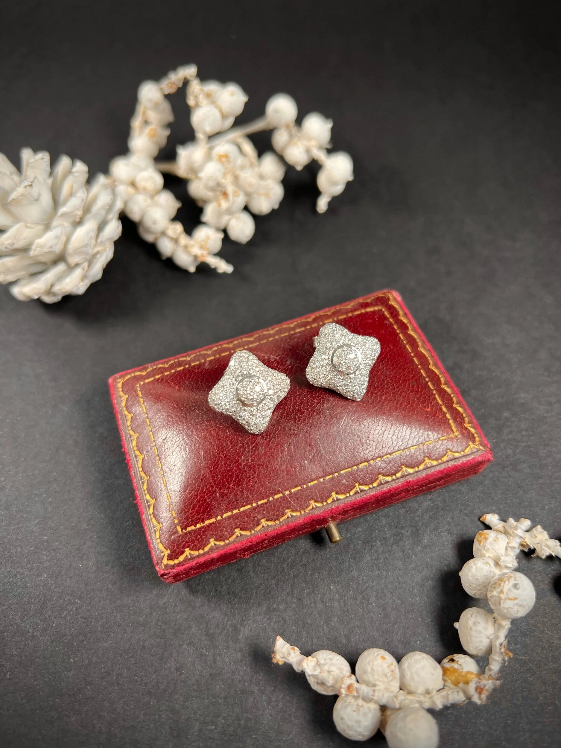 A pair of diamond cluster stud earrings in white gold, on an antique box
