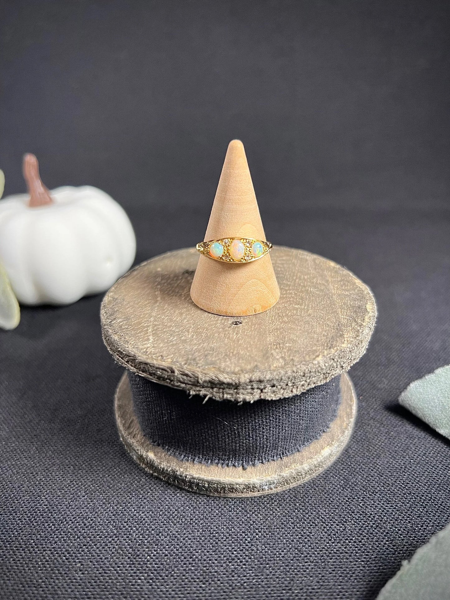 A boat-shaped gold ring with opals and diamonds, on a ring cone