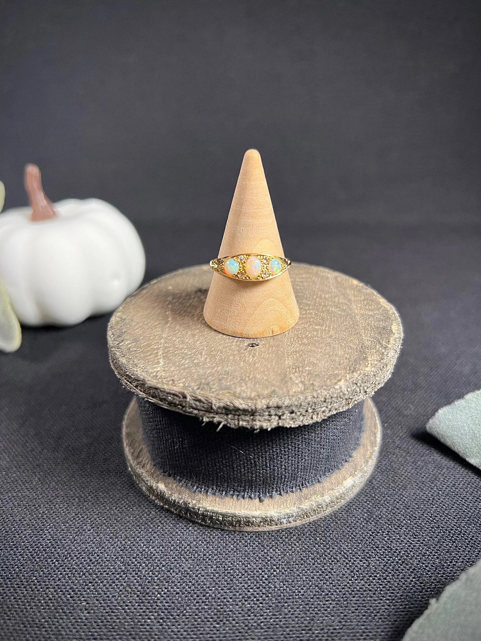 A boat-shaped gold ring with opals and diamonds, on a ring cone