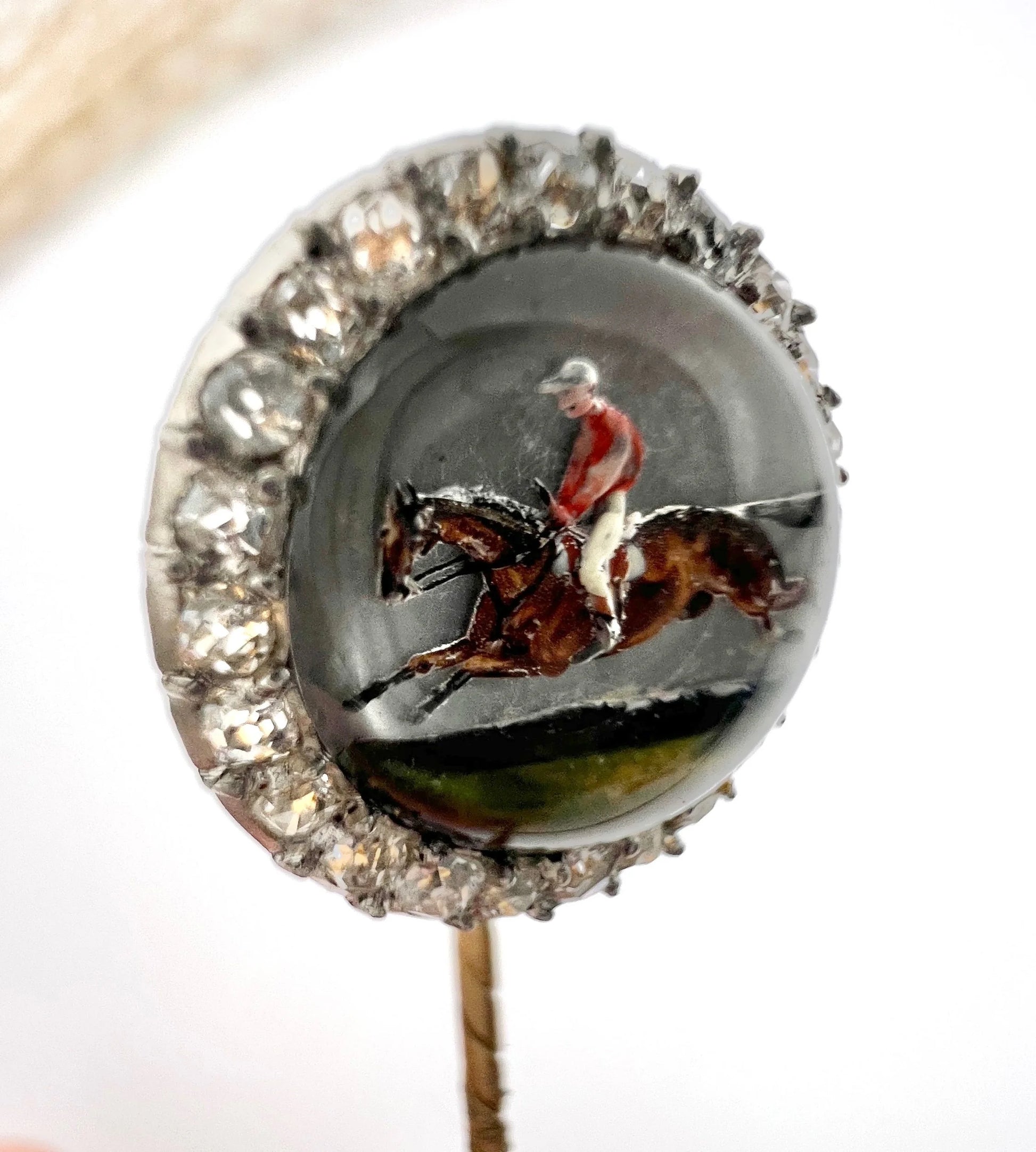 An antique Essex glass and diamond stick pin depicting a jockey riding a horse